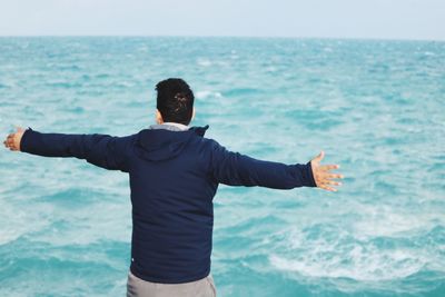 Rear view of man standing by sea against sky