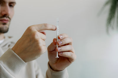 A young man holds a medicine in a syringe in his hands.