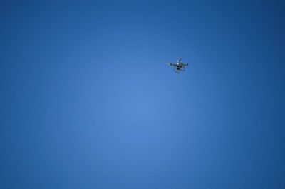 Low angle view of drone flying against clear blue sky