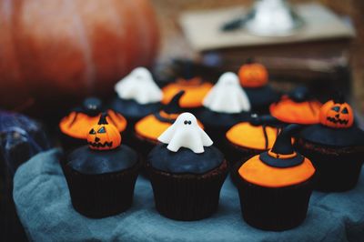 Close-up of cupcakes and pumpkin on table during halloween celebration