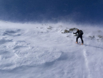 Man standing on snow covered mountain against sky