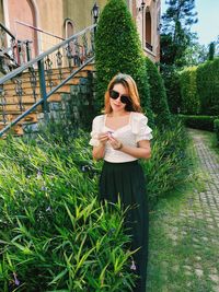 Young woman standing against plants