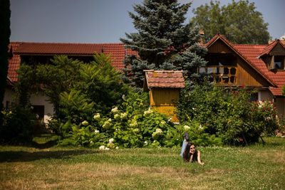 People outside house on field against trees and building