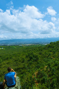 Rear view of man looking at landscape against sky