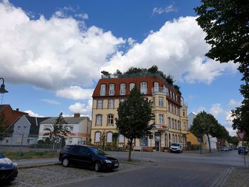 Cars on road by buildings against sky