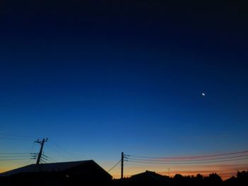 Low angle view of silhouette communications tower against sky at dusk