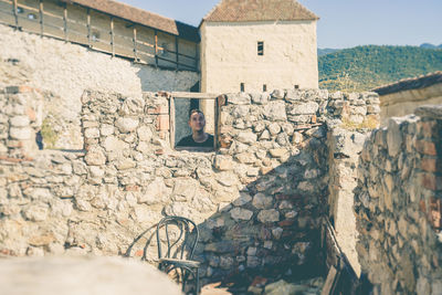 Man standing behind wall of old building