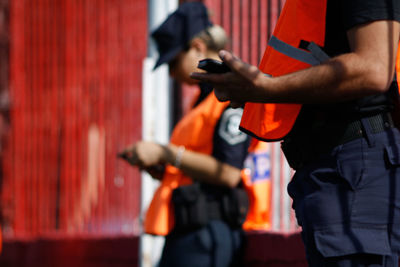 Midsection of man holding umbrella standing against wall in city