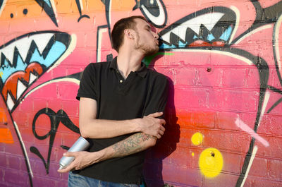 Full length of young man standing against graffiti wall