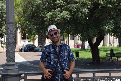 Portrait of smiling man wearing sunglasses against trees