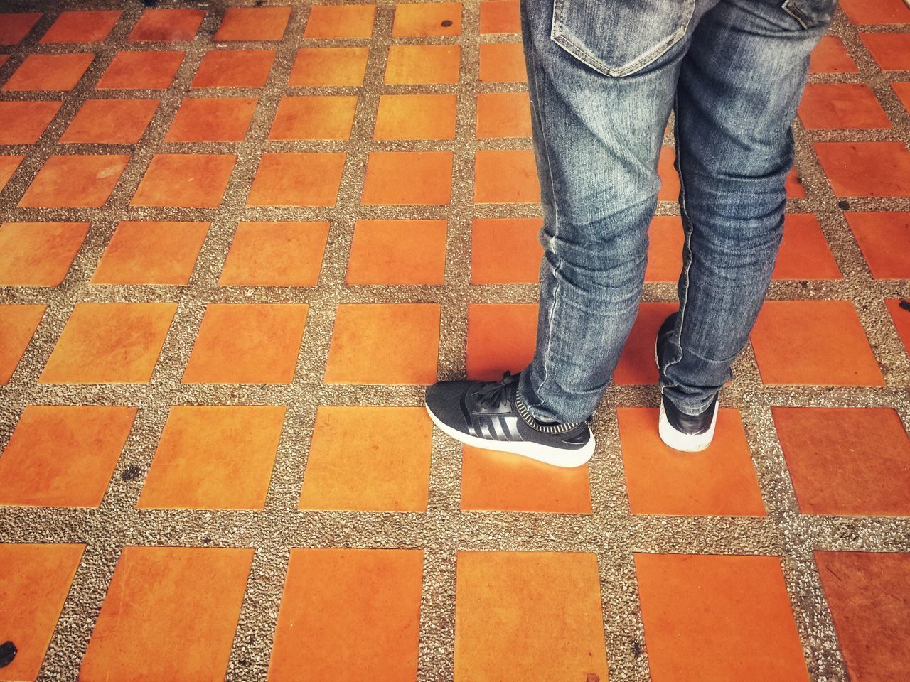 LOW SECTION OF MAN STANDING ON FOOTPATH BY TILED FLOOR