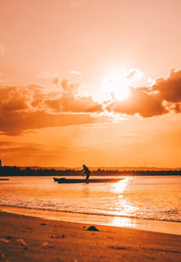 A fisherman pedaling his boat during sunset