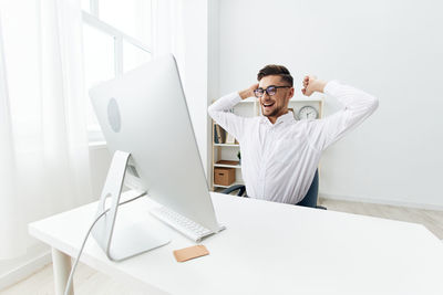 Portrait of woman using laptop while standing against white background