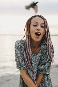 Portrait of happy young woman standing against lake