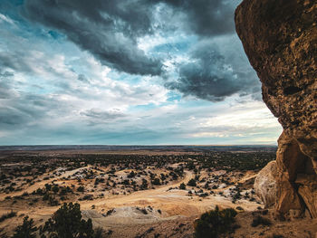 Stormy clouds over desert landscape with a rock formation to the side taken from the top of a bluff