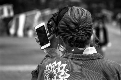 Rear view of woman using mobile phone outdoors