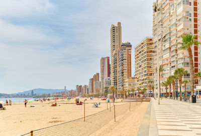 People on beach against buildings in city