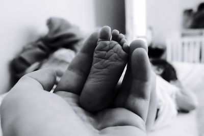 Cropped hand of father holding daughter leg at home