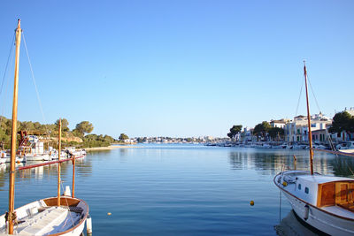 Sailboats moored in marina against clear blue sky