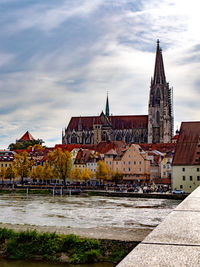 Buildings by river against sky