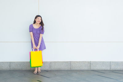 Portrait of woman standing against wall