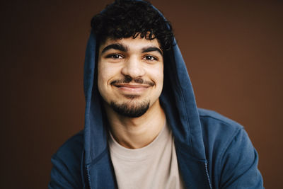 Portrait of smiling man wearing jacket against brown background