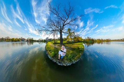 Portrait of man standing by lake against blue sky