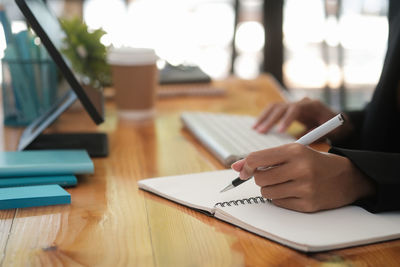 Midsection of woman writing on notepad