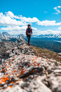 Female hiking on mountain summit above nearby mountain peaks