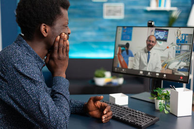 Side view of man using mobile phone while sitting on table