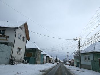Road amidst buildings against sky during winter
