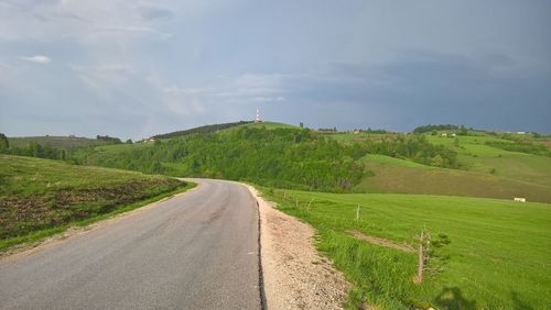 Road amidst field against sky