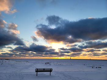 Scenic view of snow covered land against sky during sunset