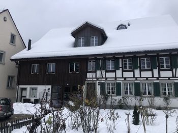 Snow covered houses by building against sky
