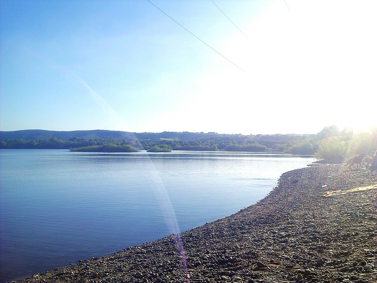 water, sun, tranquil scene, clear sky, tranquility, scenics, reflection, beauty in nature, sunlight, lake, sunbeam, blue, nature, mountain, lens flare, sky, idyllic, copy space, sea, sunny