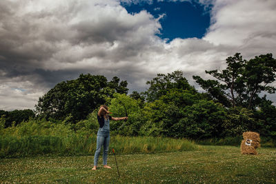 Girl shooting compound bow in open field