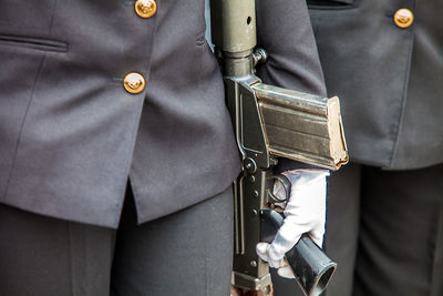 Midsection of army soldier holding rifle