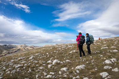 Rear view of man walking on mountain against sky