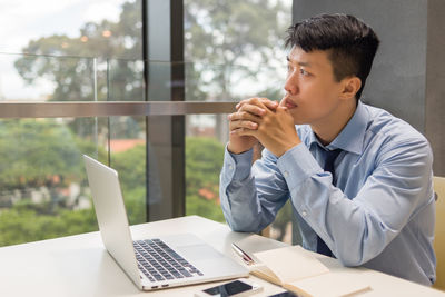 Young man using mobile phone while sitting on table