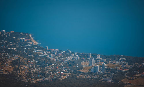 Aerial view of illuminated buildings in city against clear blue sky