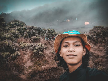 Portrait of young man standing against trees