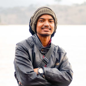 Portrait of smiling young man wearing knit hat and jacket during winter