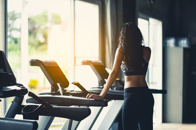 Woman standing by treadmill in gym