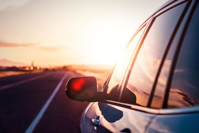 Close-up of sunglasses on road against sky during sunset