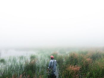 Rear view of man walking on field against clear sky