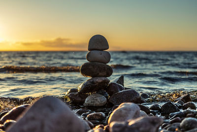 Sunset on a pebble beach where a stack of round stones stands on each other.