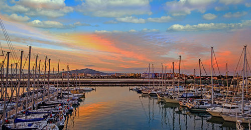 Boats moored at harbor against sky during sunset