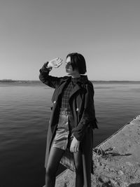 Woman standing at beach against sky