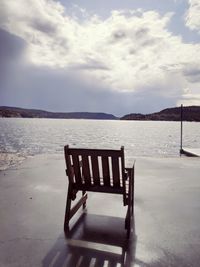 Empty chairs on beach against sky