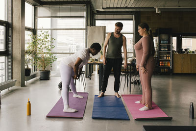 Full length of colleagues learning yoga from businesswoman at office